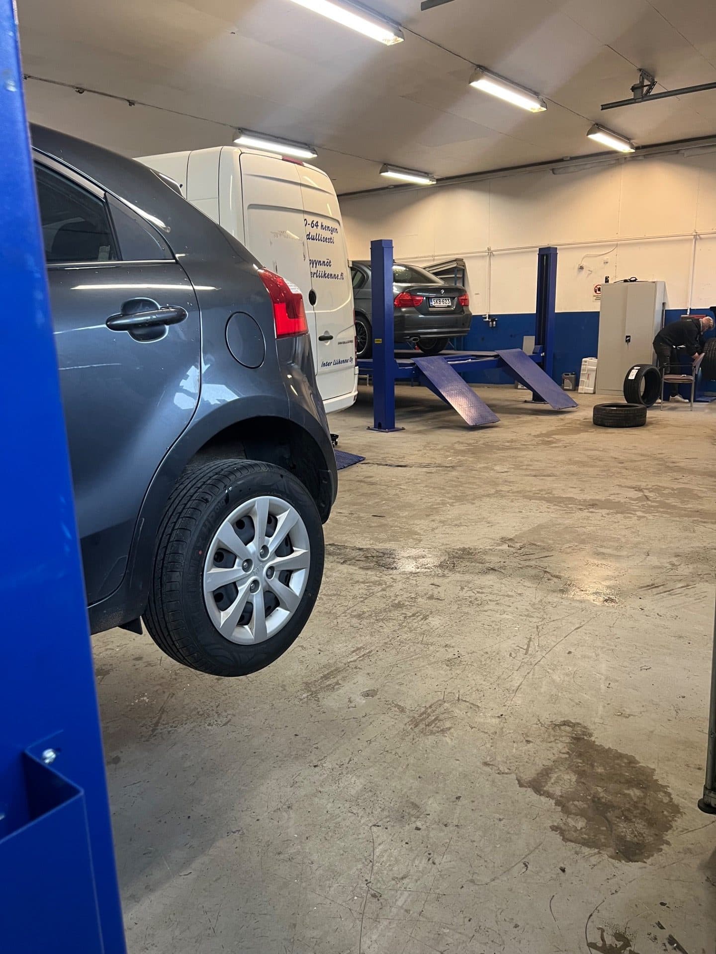 Henkilöauto nostimella korjaamohallissa Hollolassa